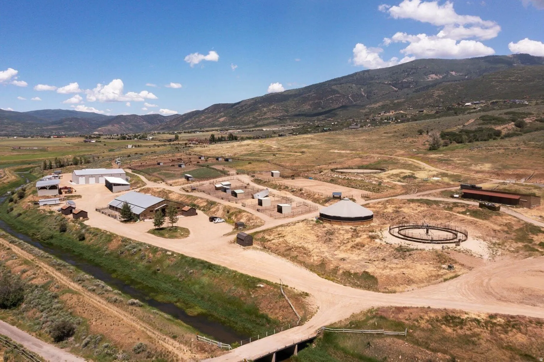 Expansive rural property featuring multiple structures, open land, and mountain backdrops