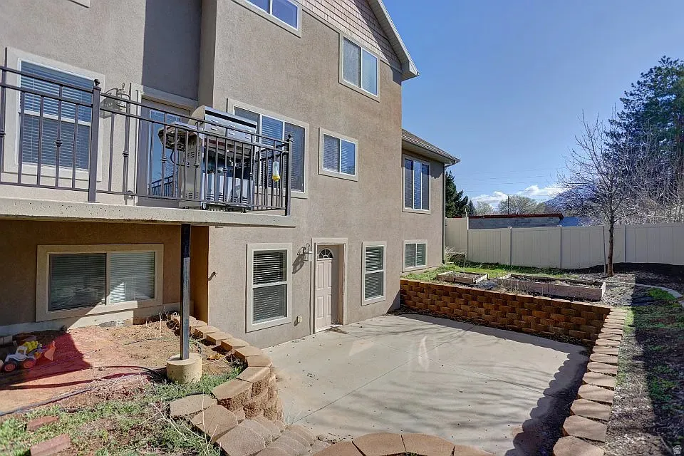 Stucco exterior featuring a second-story balcony with metal railings