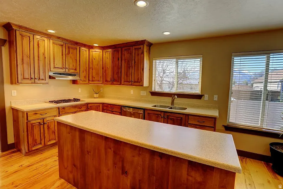 Kitchen featuring wood-finish cabinetry, light-toned countertops, and a central island