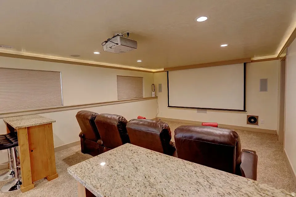 Dedicated media room featuring a large projection screen, recessed ceiling lights, and integrated speakers