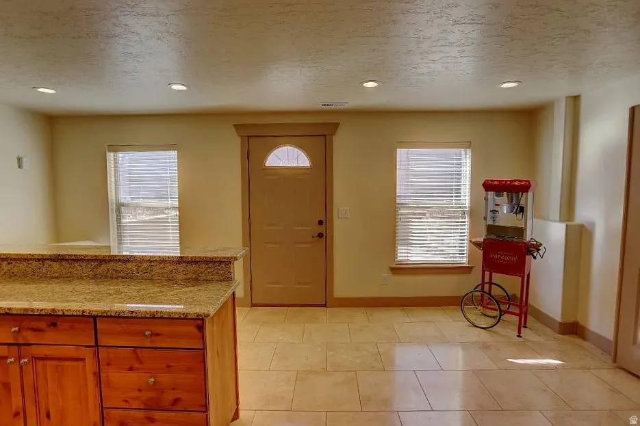 Tiled flooring extends throughout this space, featuring recessed lighting and a built-in wood cabinet with a stone countertop