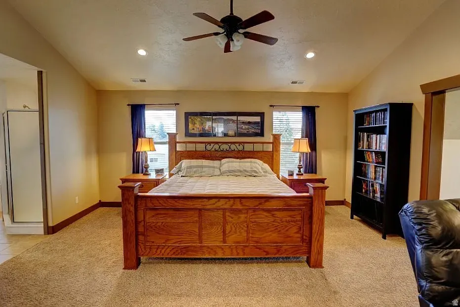 Carpeted room featuring a ceiling fan with integrated lighting, recessed lighting, and two windows with blinds and drapery
