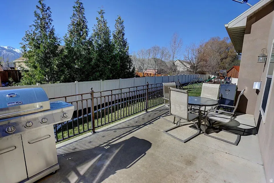 Patio featuring a concrete surface, black metal railing, and a vinyl privacy fence
