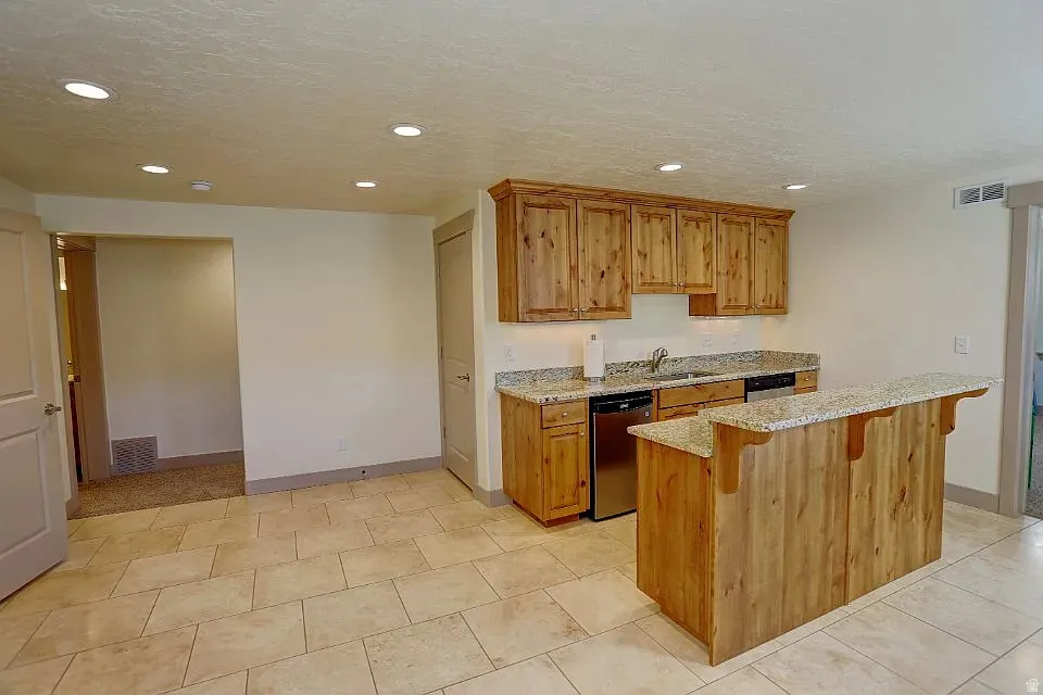 Kitchenette featuring light wood cabinetry, stone countertops, stainless steel appliances, and recessed lighting