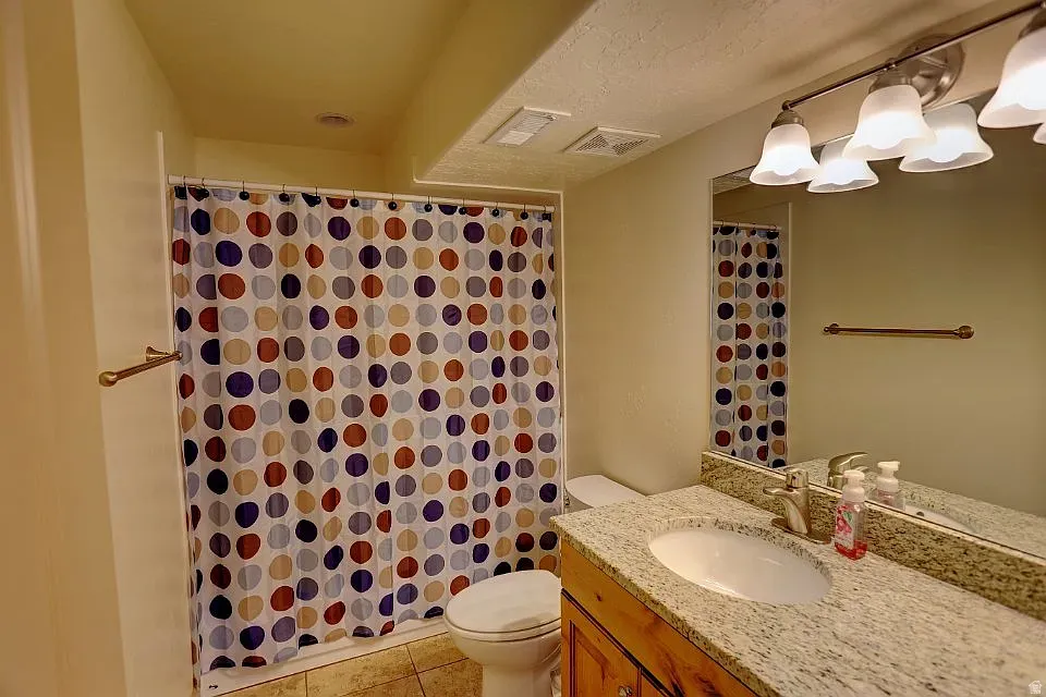 Bathroom featuring a vanity with a light-toned granite countertop, undermount sink, and brushed nickel faucet