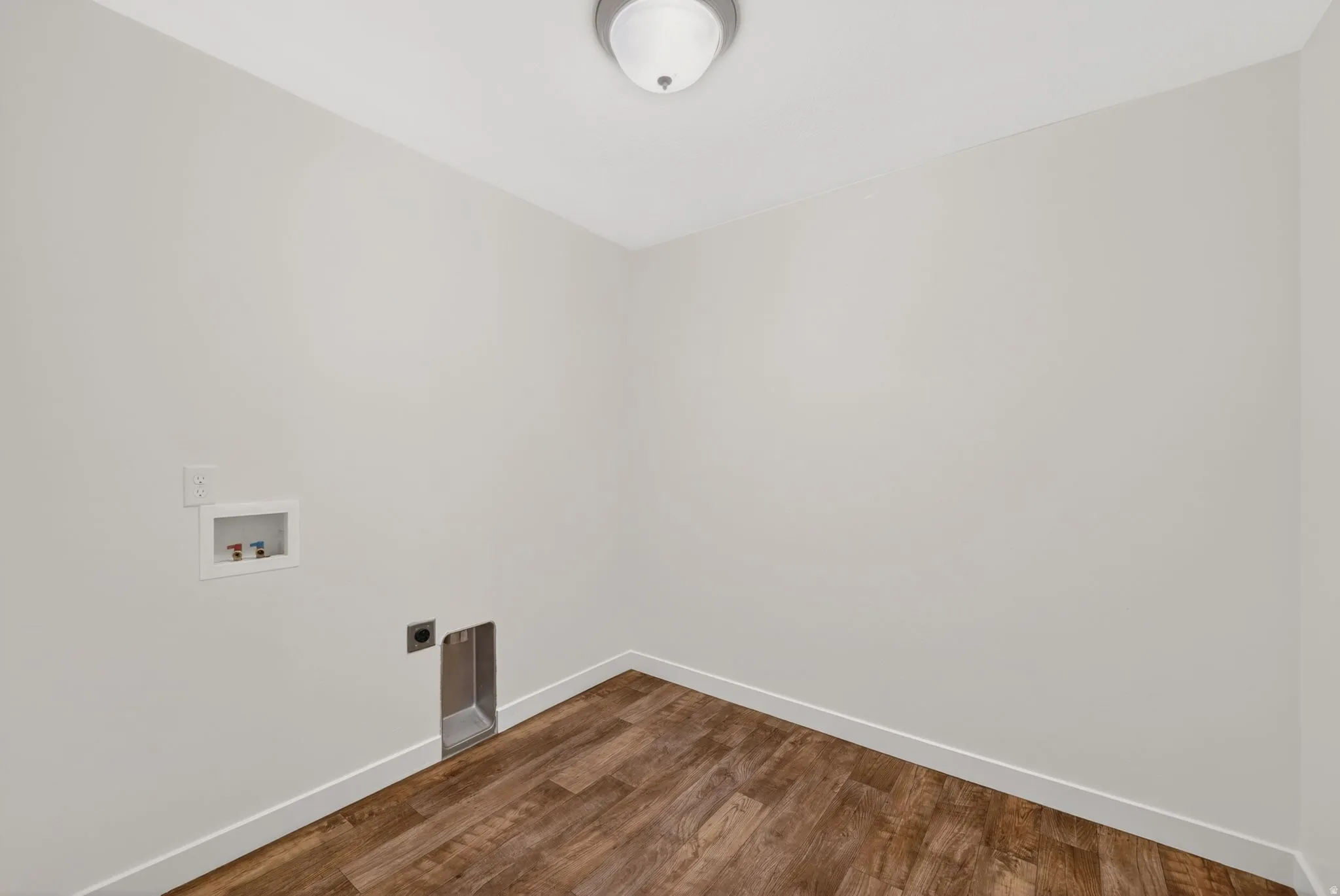 Utility space featuring wood-finish flooring, light gray walls, and white baseboards