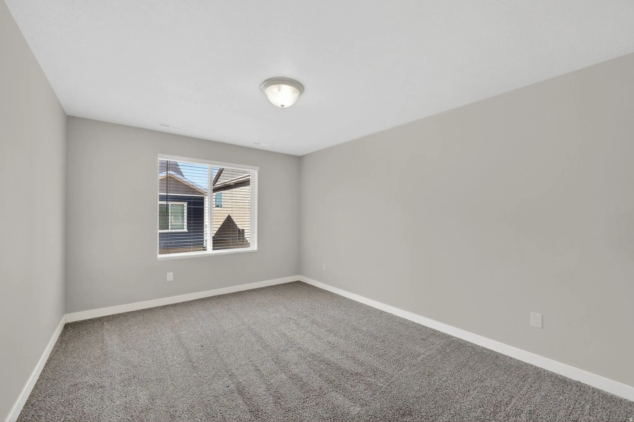 Room featuring neutral-toned walls, plush carpet flooring, a single window with horizontal blinds, a white ceiling, and a flush-mount ceiling light fixture