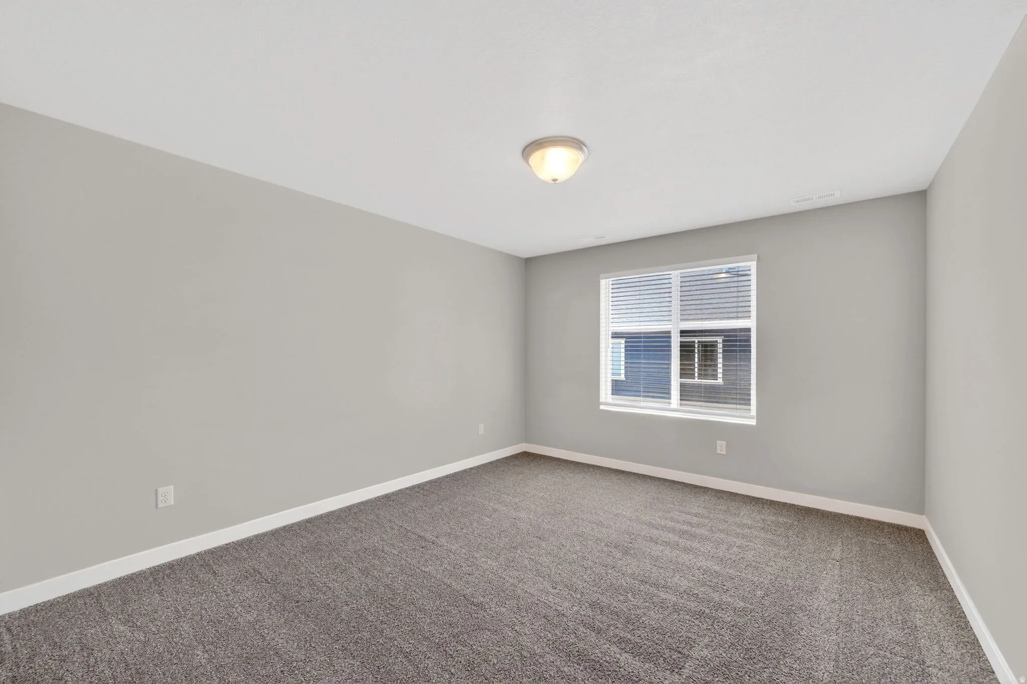 Room featuring neutral gray walls, a window with blinds, and gray carpet flooring