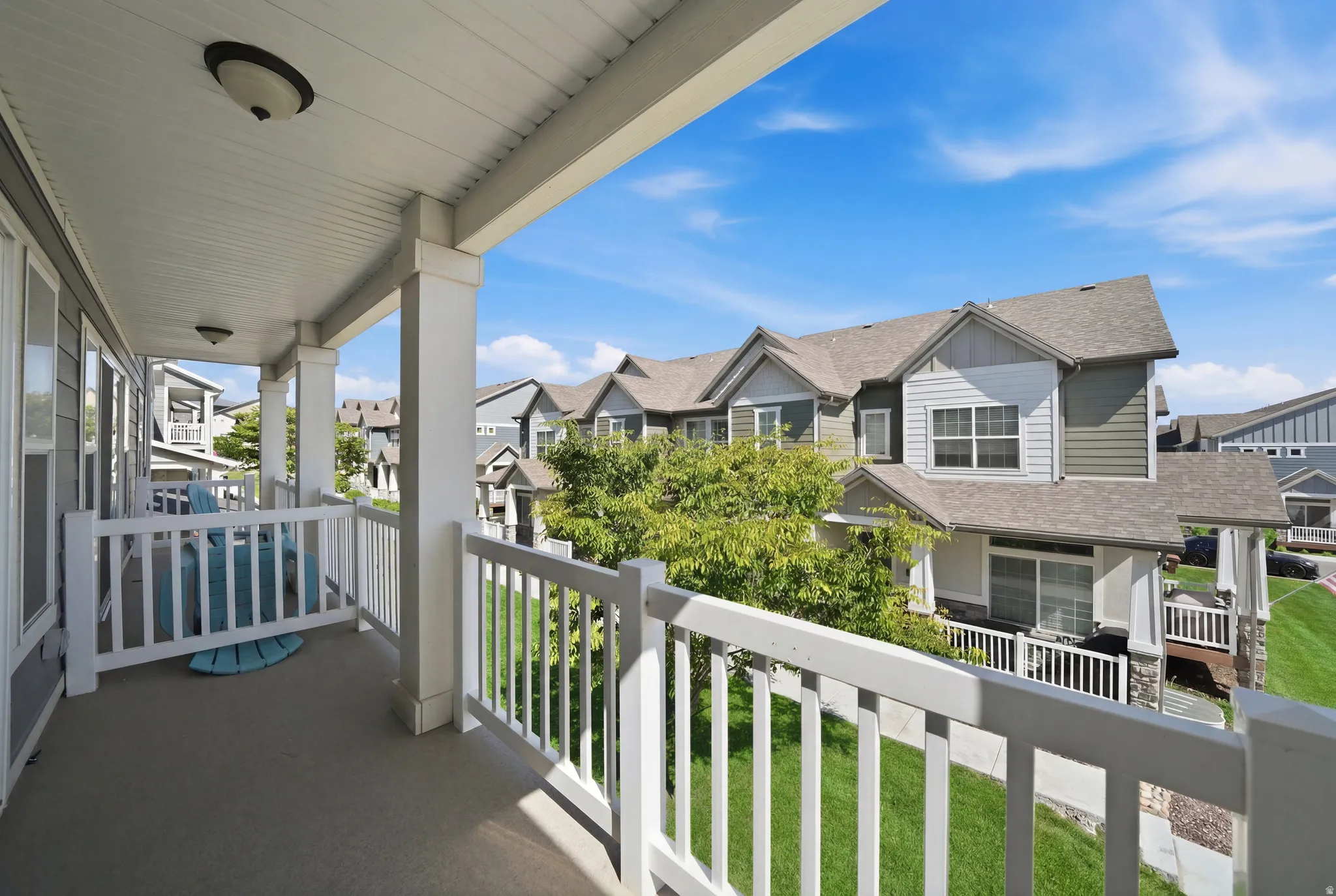 Covered outdoor balcony featuring a concrete floor and white railing