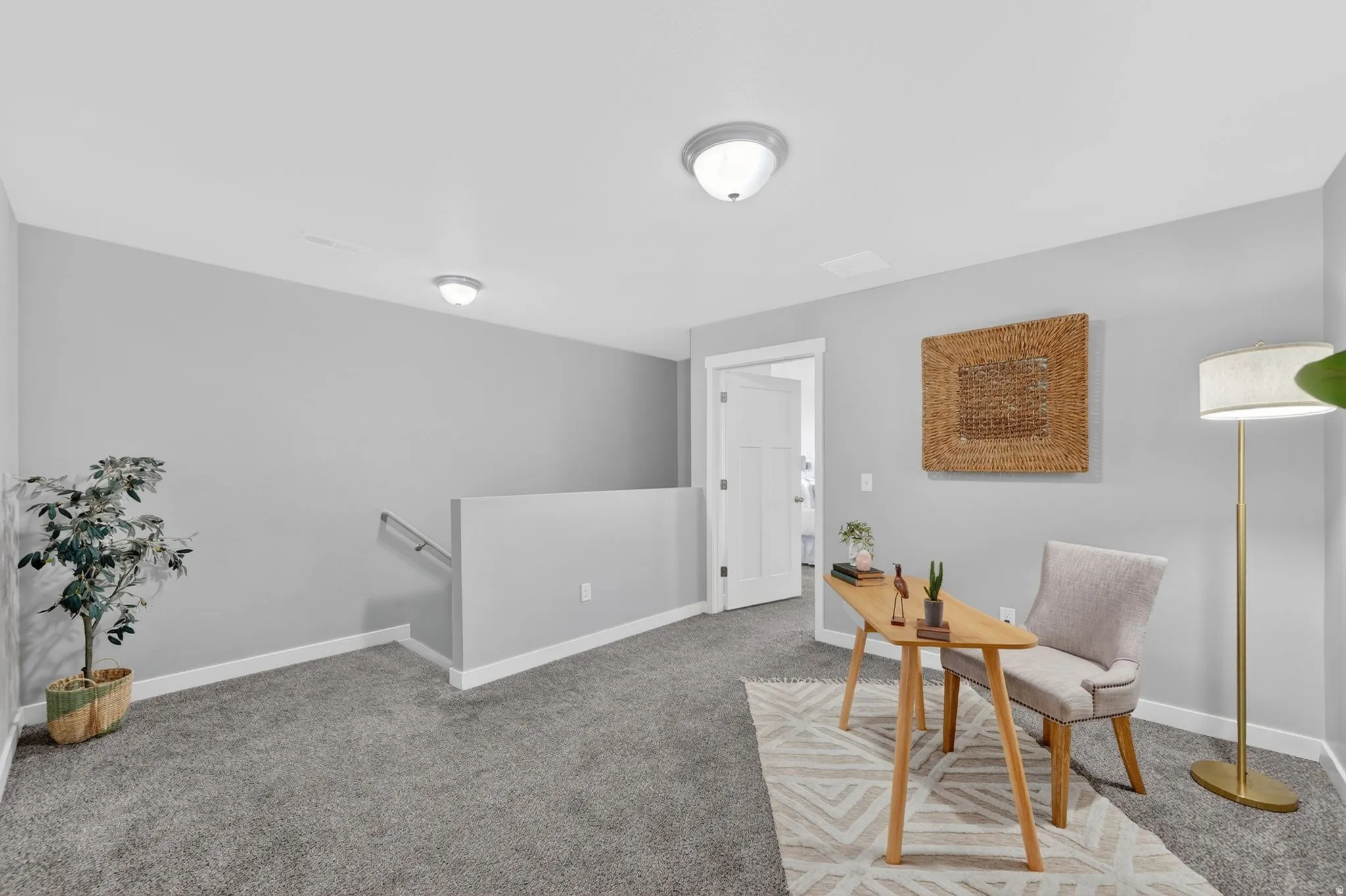 Carpeted upper-level landing featuring a white painted railing, ceiling-mounted light fixtures, and a white interior door frame