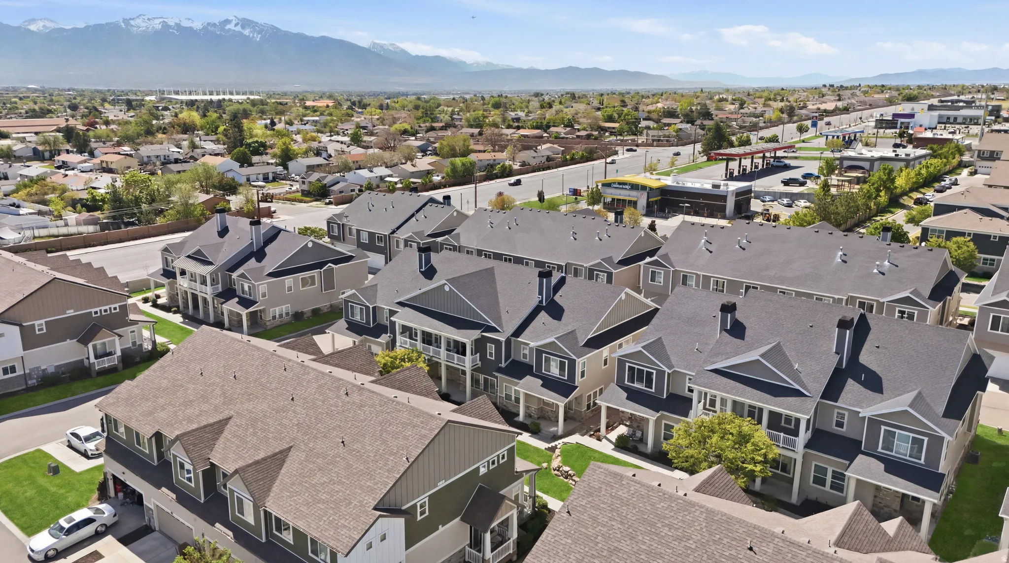 Modern residential community featuring multi-story townhomes with dark shingle roofs, light-colored siding, and structured landscaping