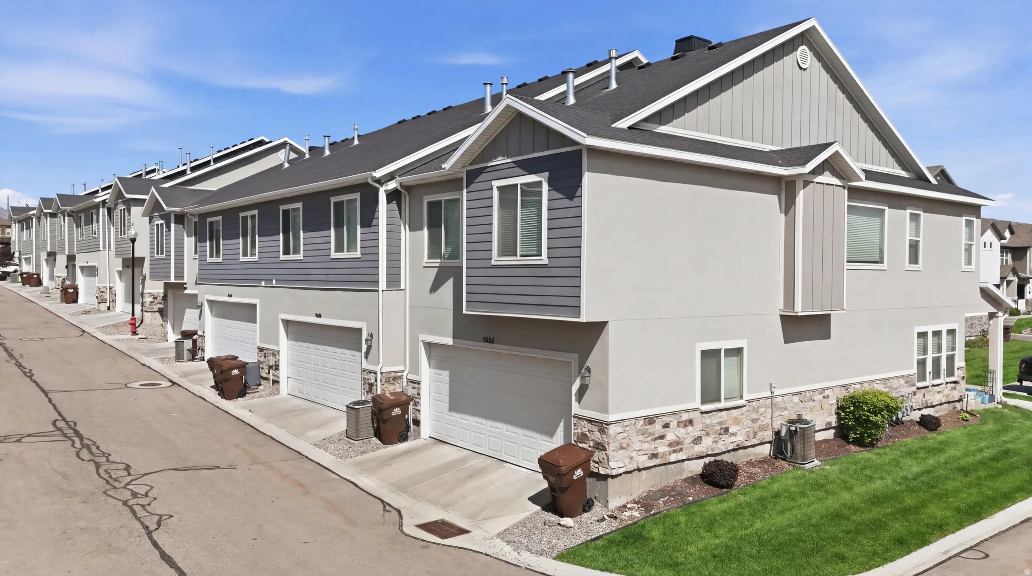 Modern townhome exterior featuring a combination of stucco, horizontal siding, and stone veneer