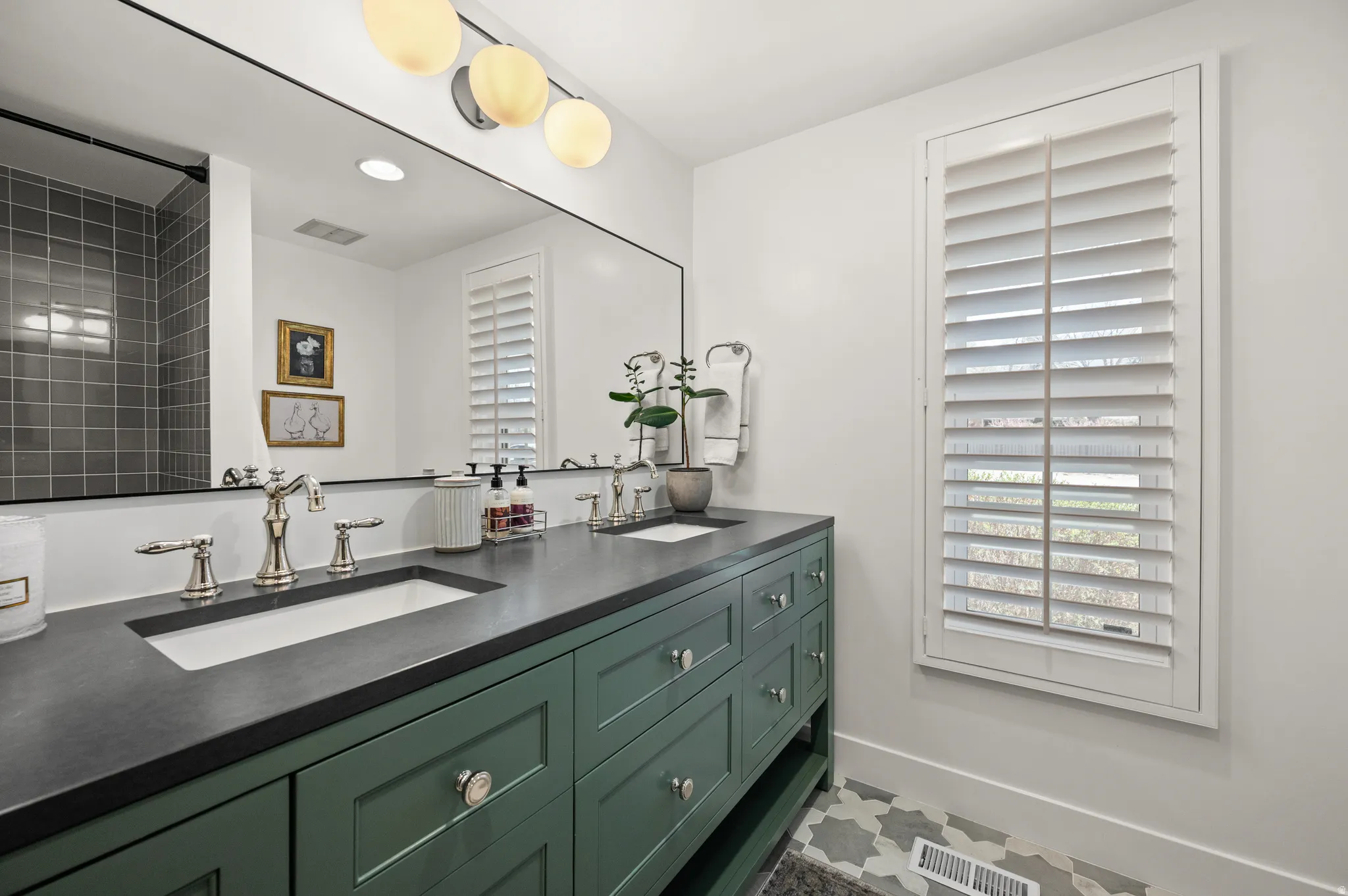 Dual vanity with a dark countertop and green cabinetry