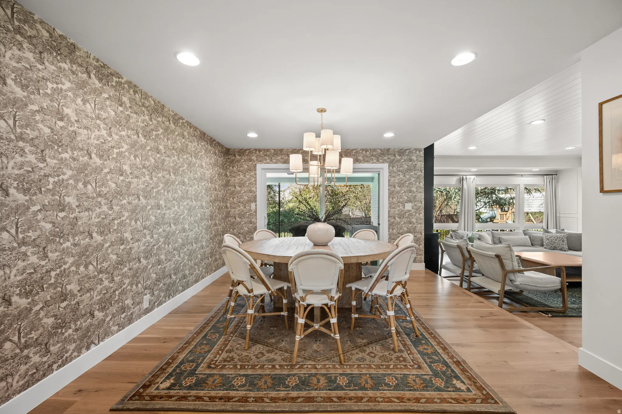 Dining area featuring a decorative chandelier, wood-finish flooring, recessed lighting, and a large window overlooking exterior landscaping