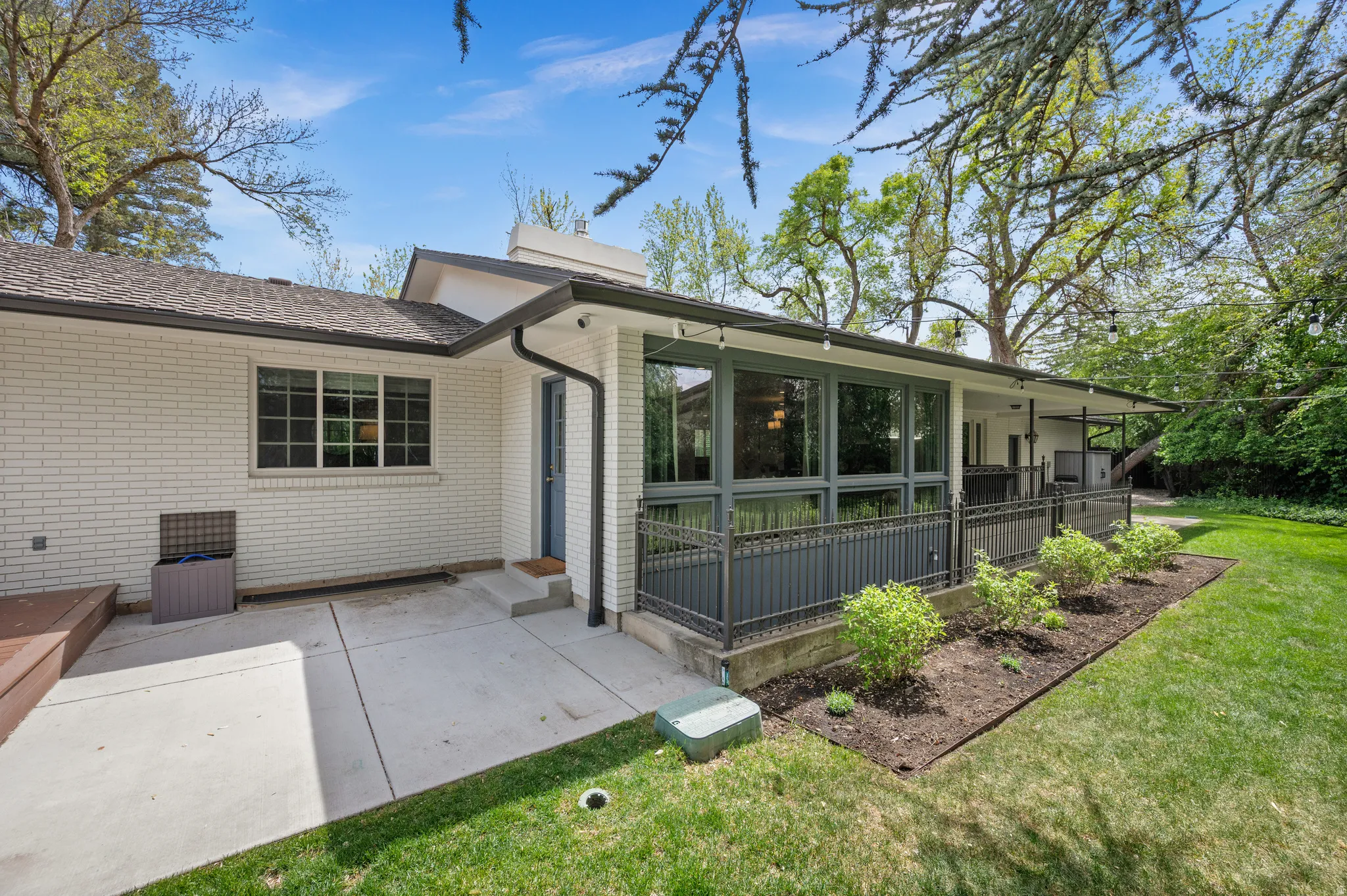 Exterior featuring white brick siding, a concrete patio, and a covered deck area