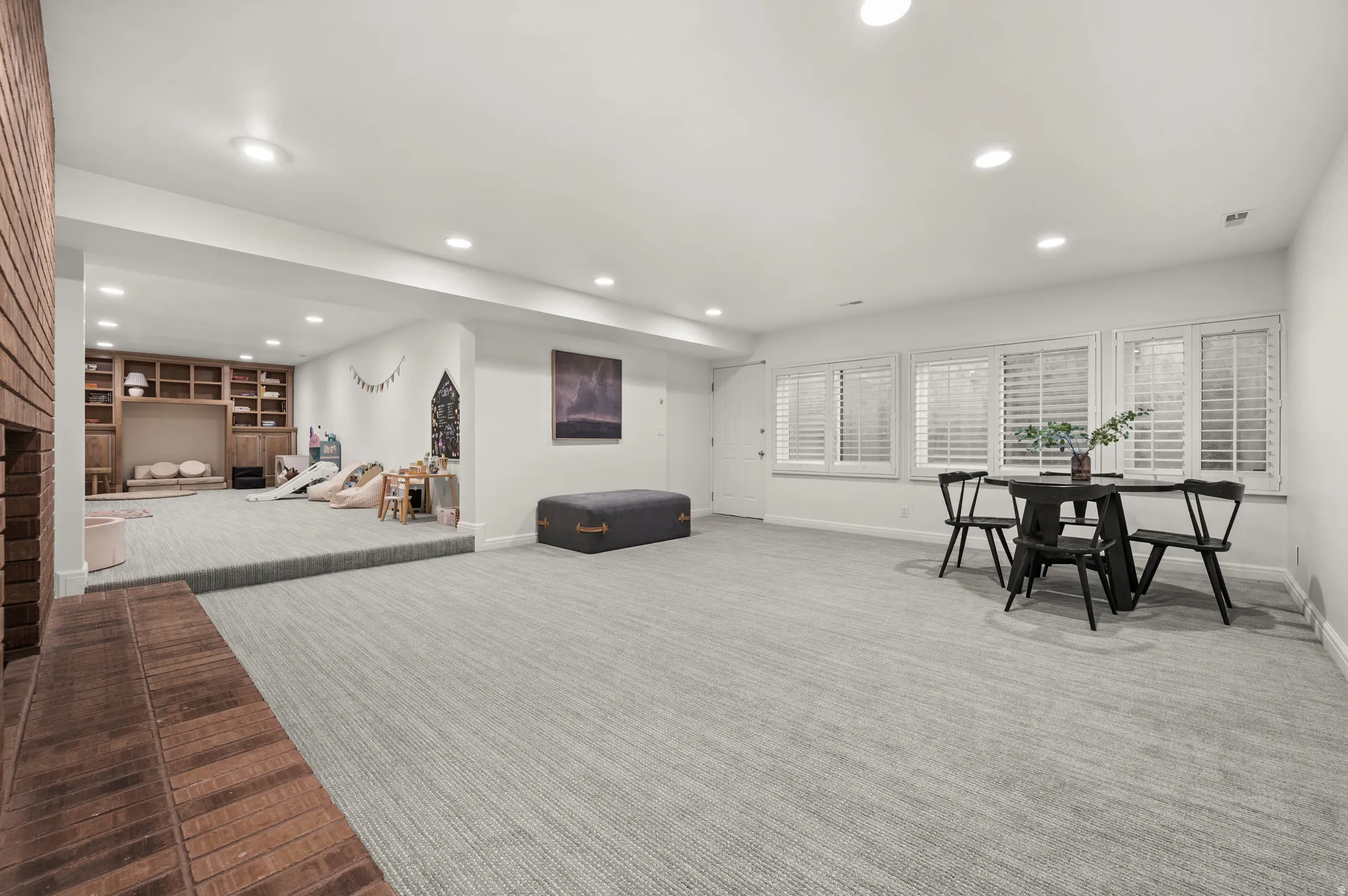 Spacious lower level featuring light-toned carpet, recessed lighting, and multiple windows with plantation shutters