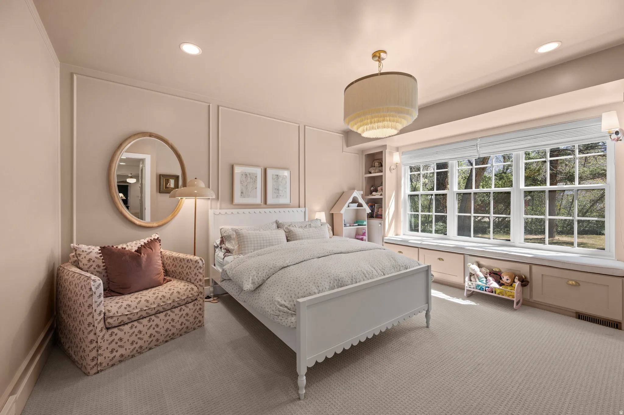 Expansive window bank with built-in storage and seating, recessed lighting, central chandelier, wall paneling, and carpet flooring