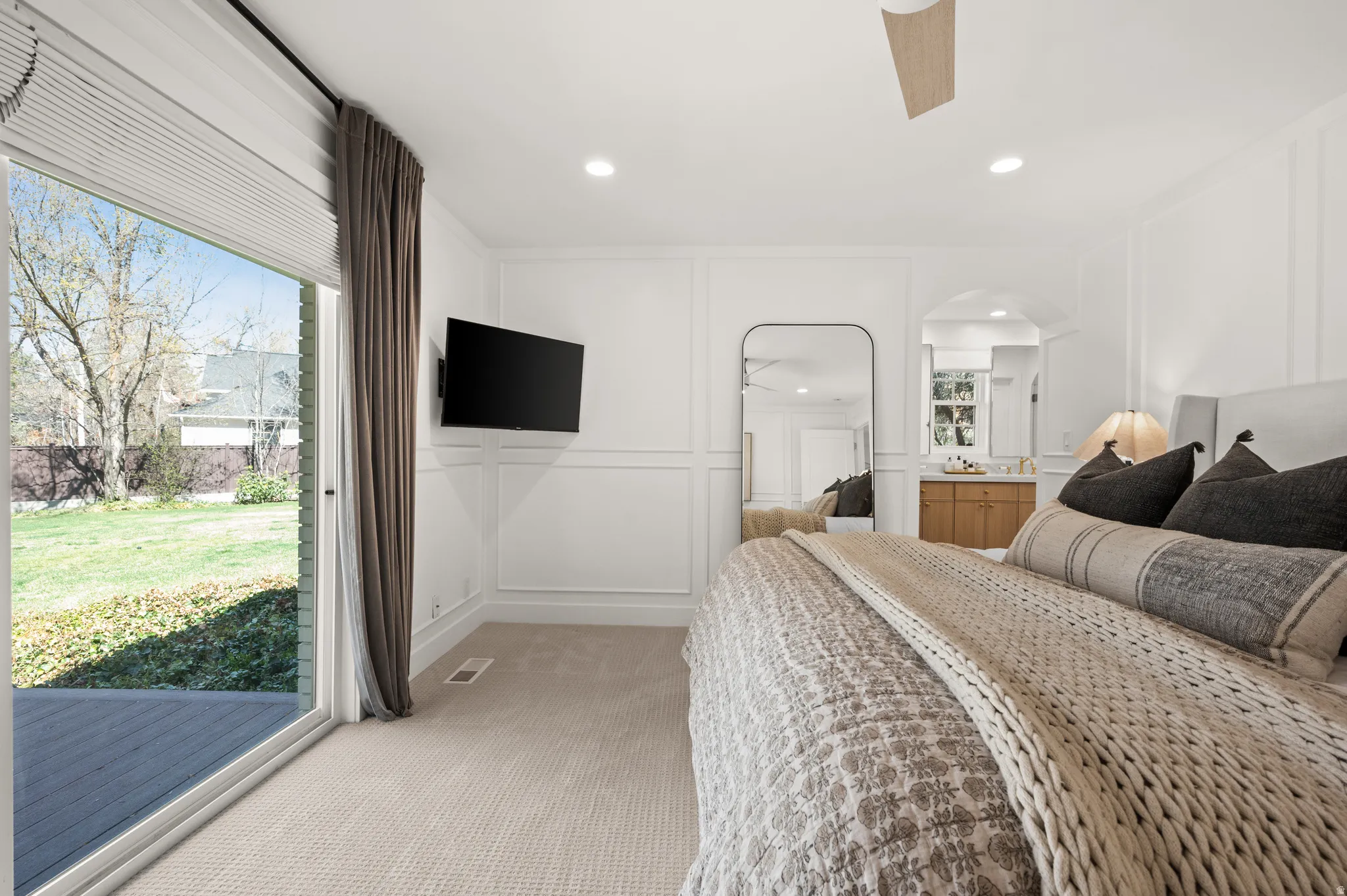Carpeted bedroom with a sliding glass door opening to a deck and backyard