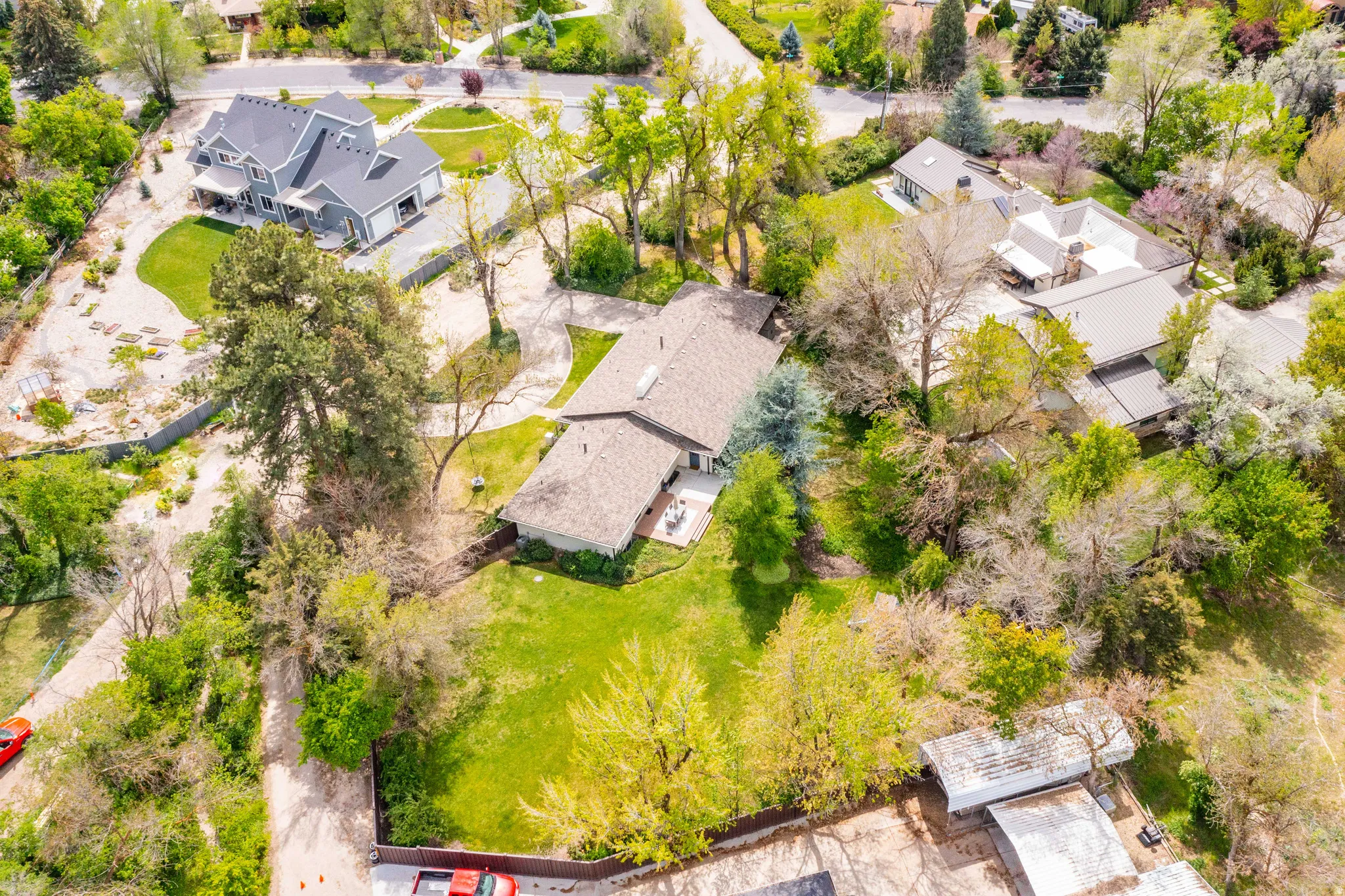 Expansive property featuring mature trees, a lush green lawn, and surrounding foliage