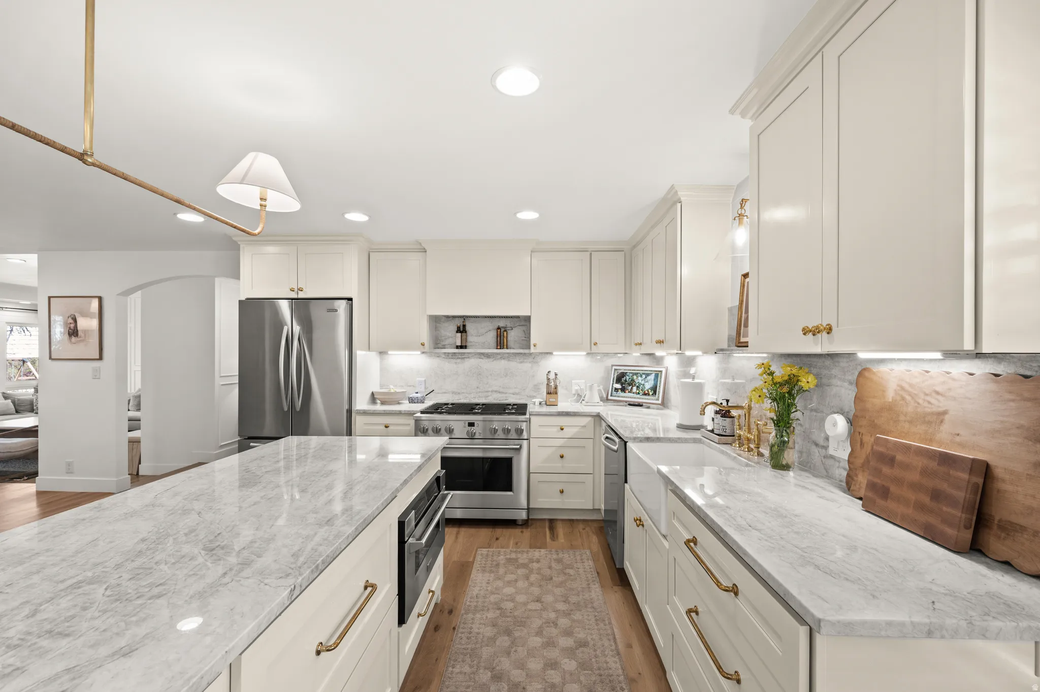 Kitchen featuring an expansive island with a stone countertop, recessed lighting, wood-finish flooring, a stainless steel refrigerator, and a stainless steel range