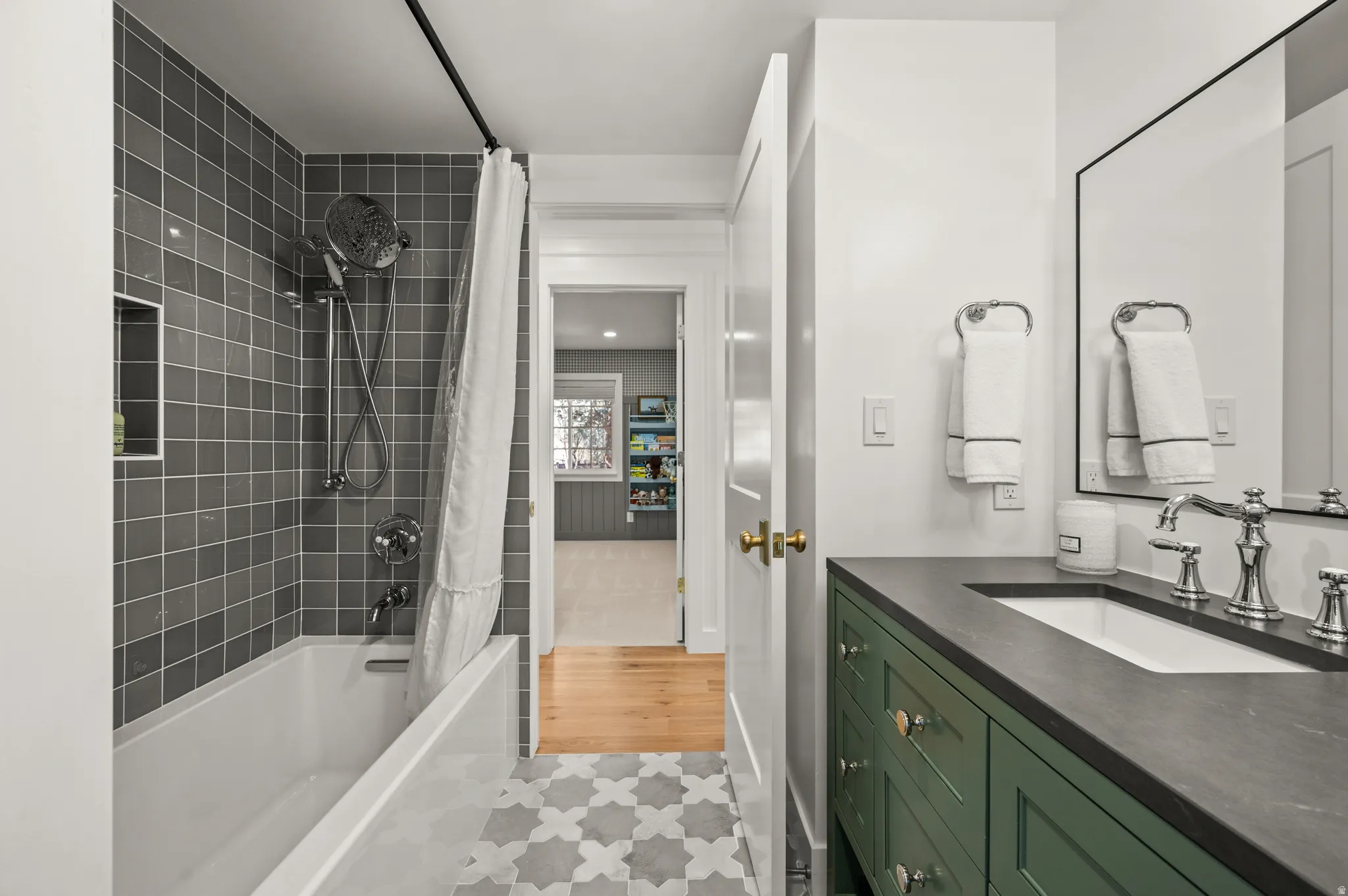 Bathroom featuring a green vanity with a dark countertop, white undermount sink, and polished chrome fixtures