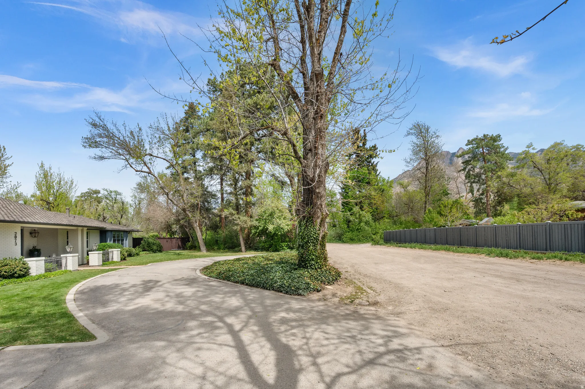 Asphalt driveway leading to a residence with a covered front porch and exterior lighting