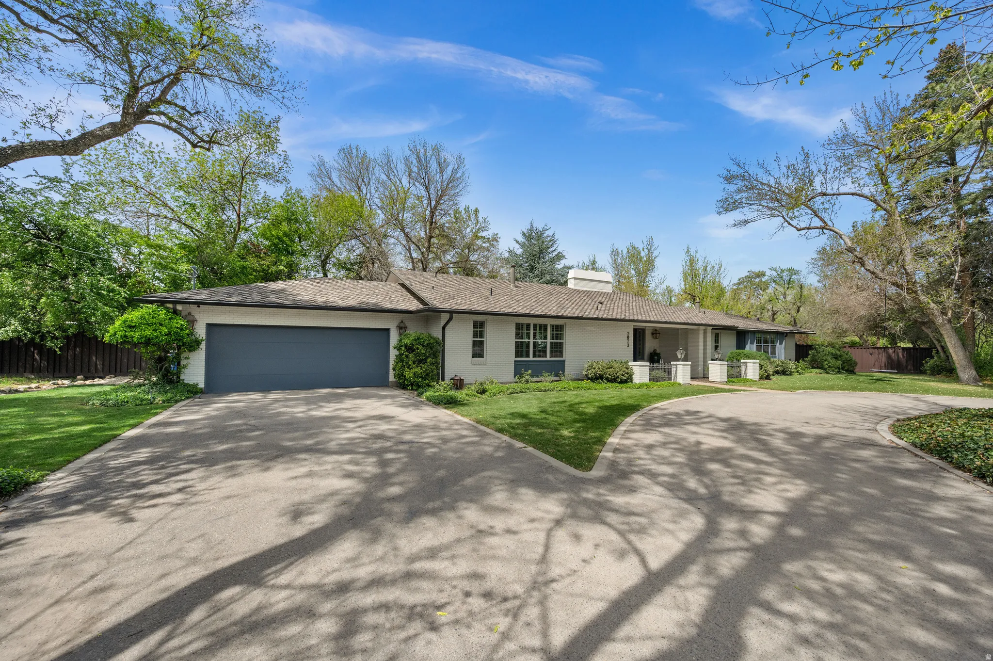 Single-story residence featuring a gray garage door, white exterior, and a tiled roof