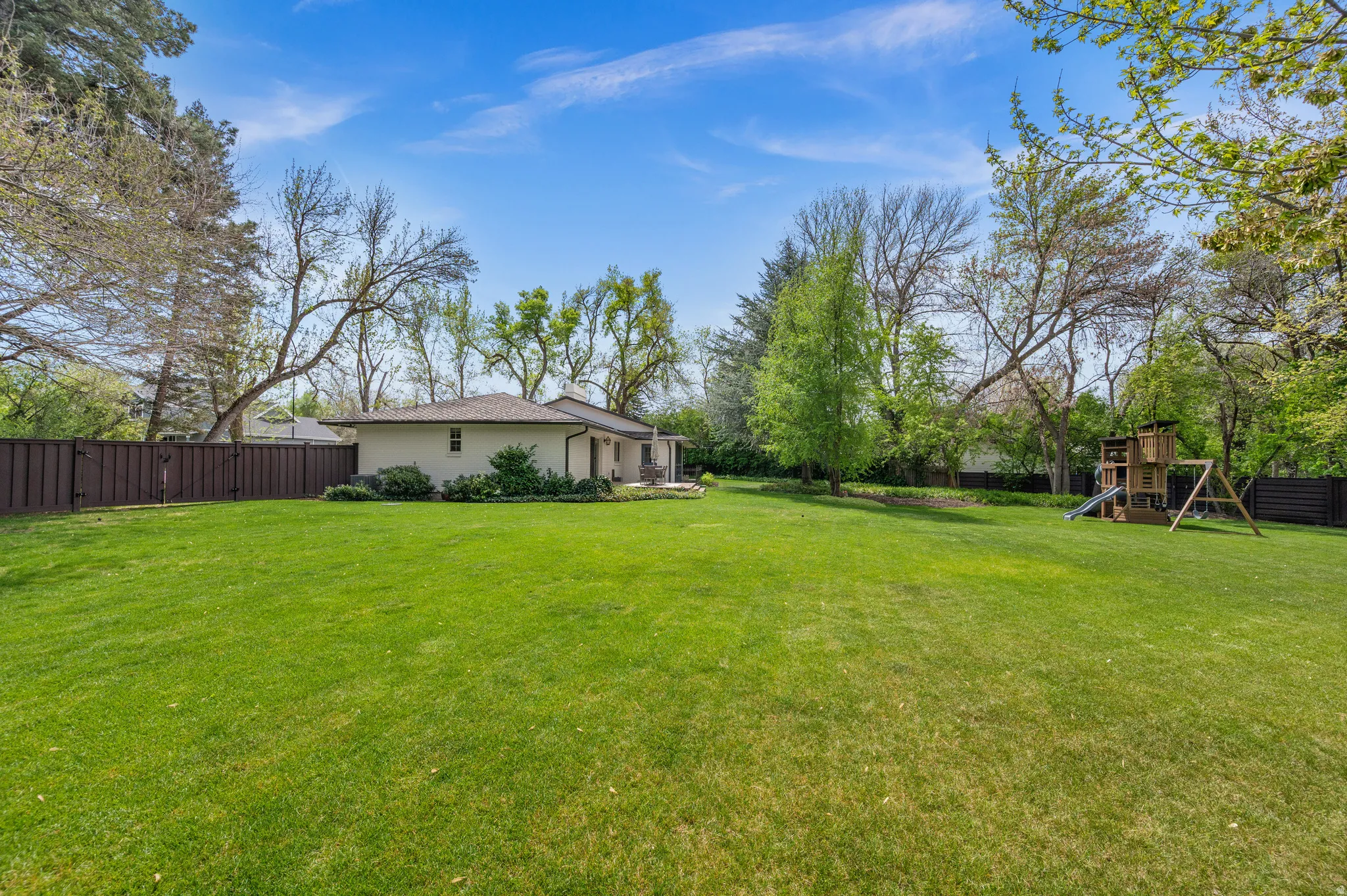 Expansive green lawn with a privacy fence and mature trees