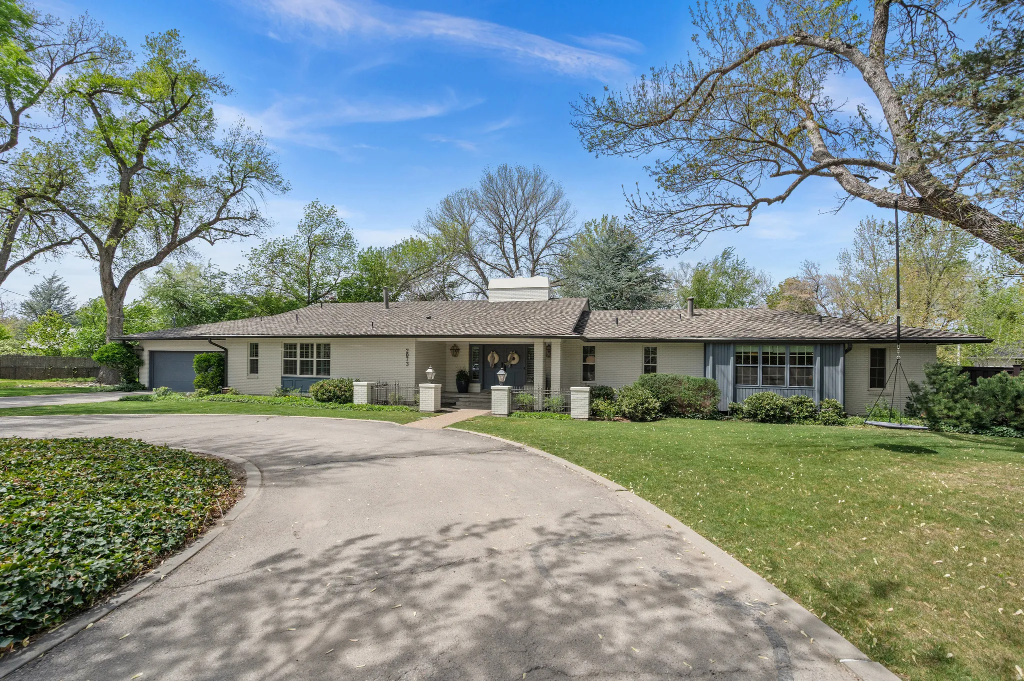 Ranch-style residence featuring a prominent circular driveway, an attached garage, and a covered entry porch