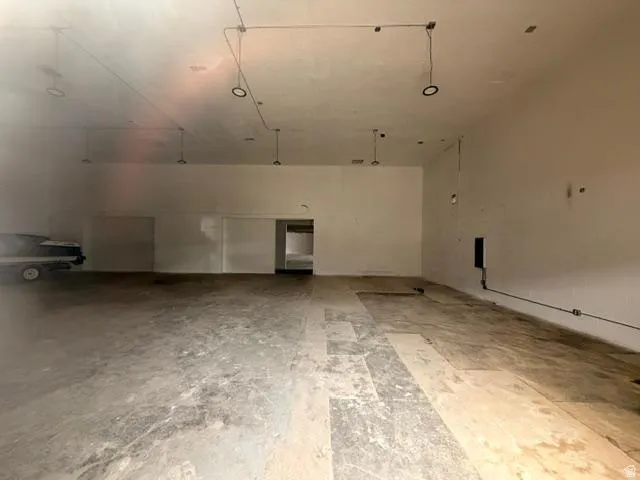 Spacious interior featuring a concrete floor, high ceilings, exposed conduit, recessed lighting fixtures, and a large open doorway