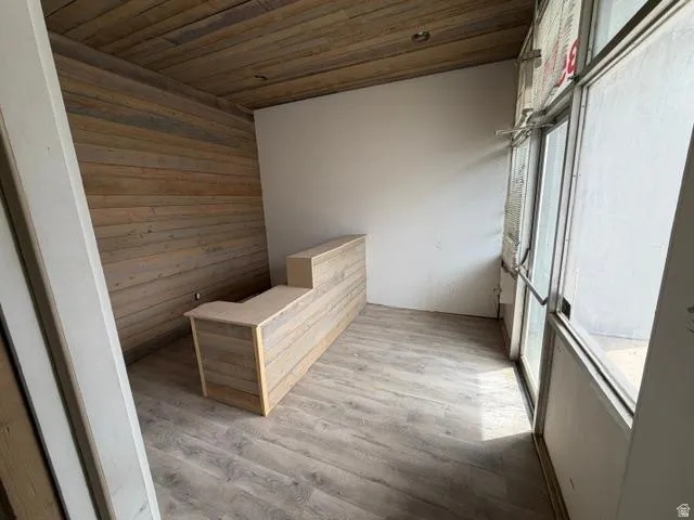 Compact entry area featuring a built-in wood-finish reception desk, wood-panel accent wall, and wood-finish ceiling