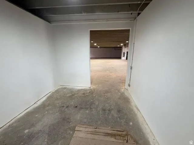 White interior walls with a concrete floor and exposed ceiling joists