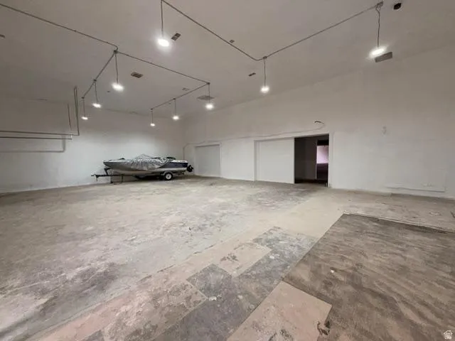 Spacious open interior featuring concrete flooring, white painted walls, and exposed conduit lighting fixtures