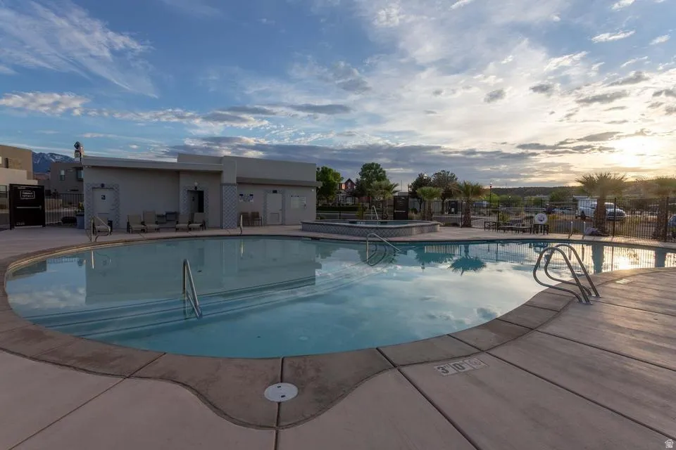Freeform swimming pool with integrated spa, surrounded by a concrete deck and mature palm trees