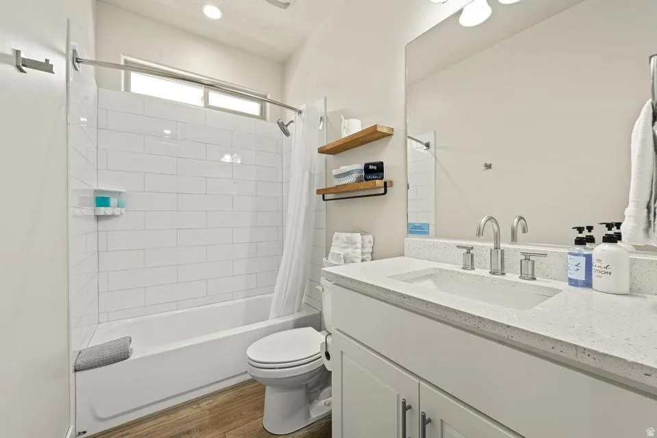 Bathroom featuring a white subway tile tub surround, a window above the tub, and wood-finish flooring
