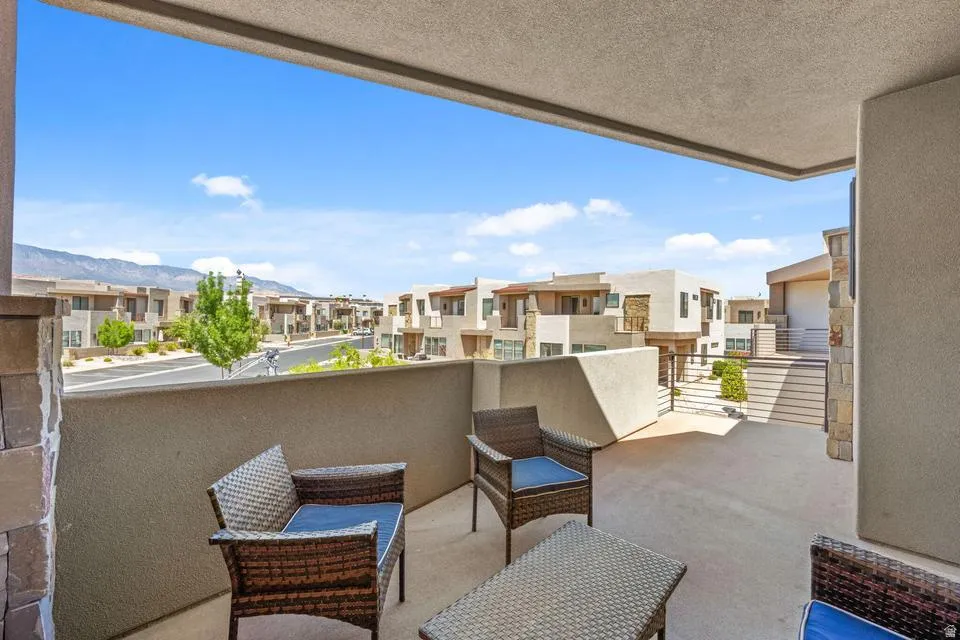 Expansive outdoor balcony featuring a concrete surface, a stucco privacy wall, and a stone-clad pillar