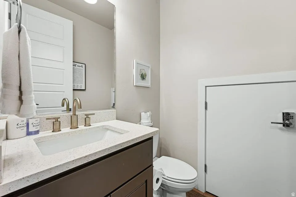 Vanity featuring a speckled countertop and a rectangular undermount sink with a brushed gold-tone faucet