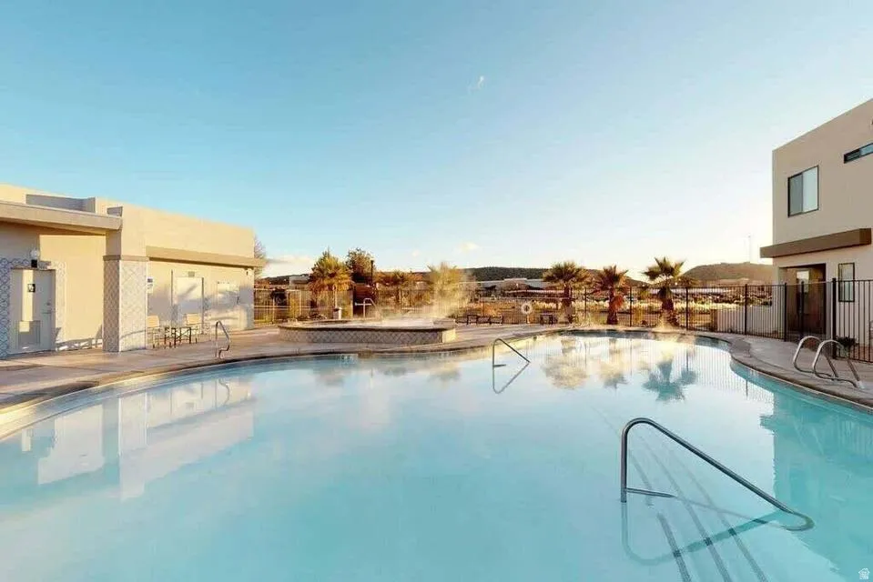 Curved swimming pool featuring integrated spa and surrounding deck