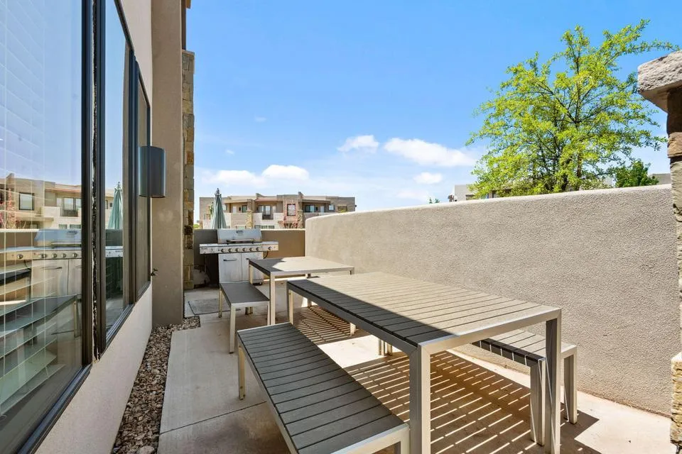 Private outdoor patio featuring a built-in barbecue grill, concrete flooring, and a stone accent wall