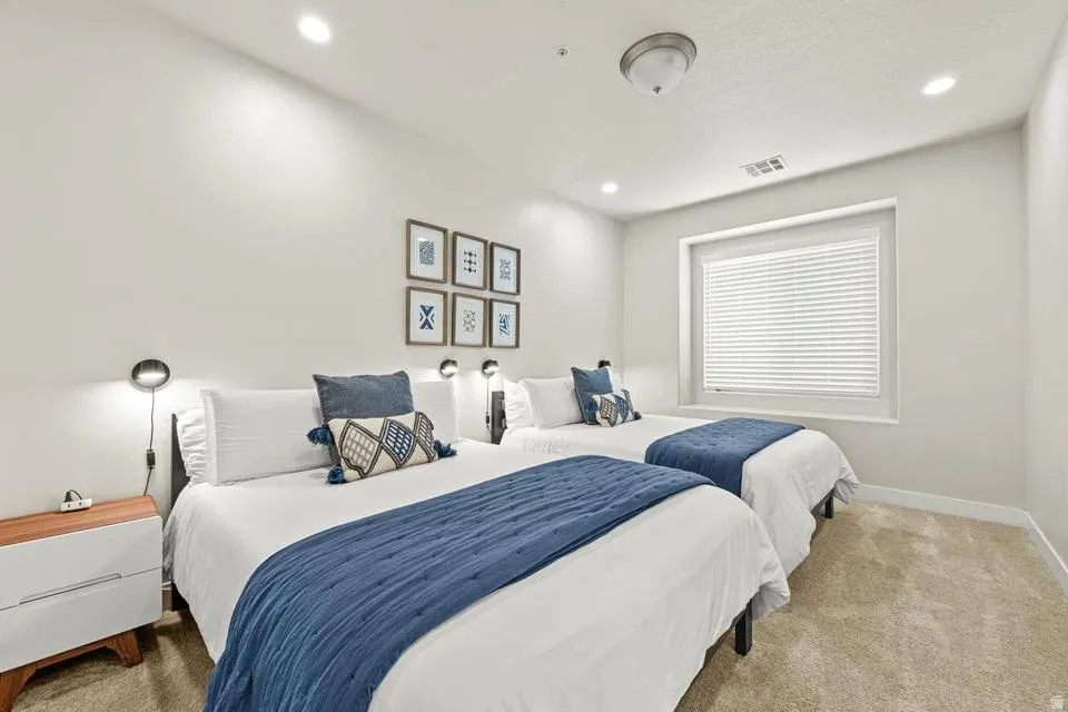 Carpeted room featuring a window with white blinds, recessed lighting, and wall-mounted sconces