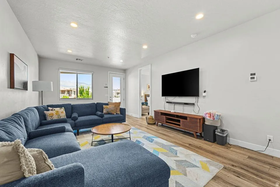 Spacious living area featuring wood-finish flooring, recessed lighting, and white walls