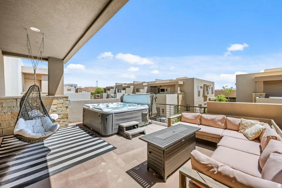 Expansive outdoor patio featuring a built-in hot tub, concrete flooring, and a partial overhead covering