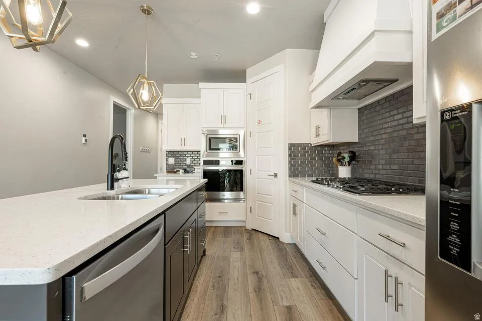Kitchen featuring a central island with an undermount sink, light-toned countertops, and wood-finish flooring
