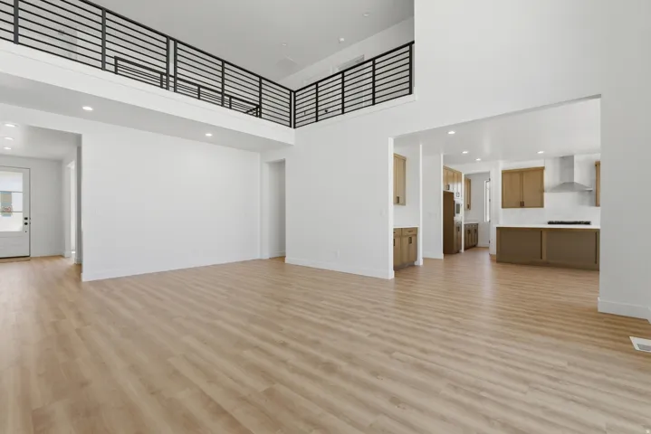 Spacious living area featuring wood-finish flooring, a double-height ceiling, and a modern horizontal slat railing