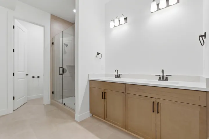Contemporary bathroom featuring a light wood-finish double vanity with white countertops and dual sinks