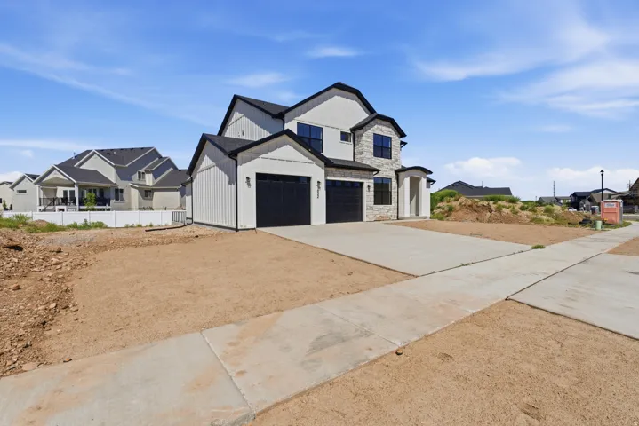 Modern exterior featuring vertical siding, stone accents, black-framed windows, a two-car garage, and a concrete driveway