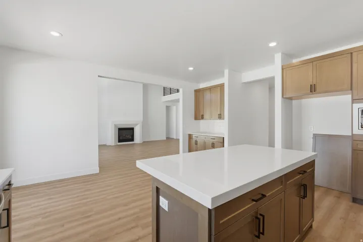 Spacious kitchen island with a light-toned countertop, wood-finish cabinetry, and black hardware