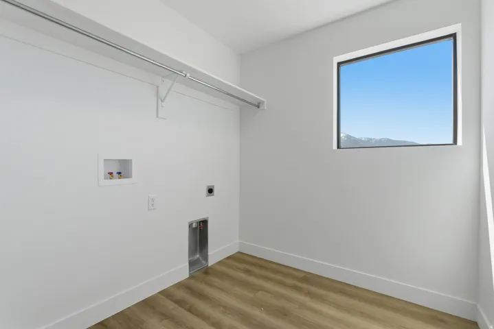 Laundry area featuring wood-finish flooring, white walls, and a window with mountain scenery