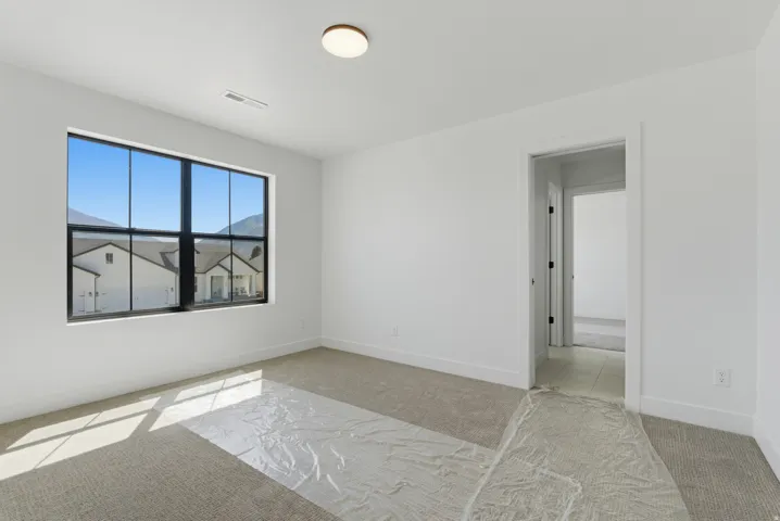 Spacious room featuring neutral carpeting, white walls, and a large black-framed window