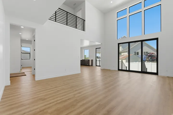 Spacious interior with high ceilings, wood-finish flooring, and abundant natural light